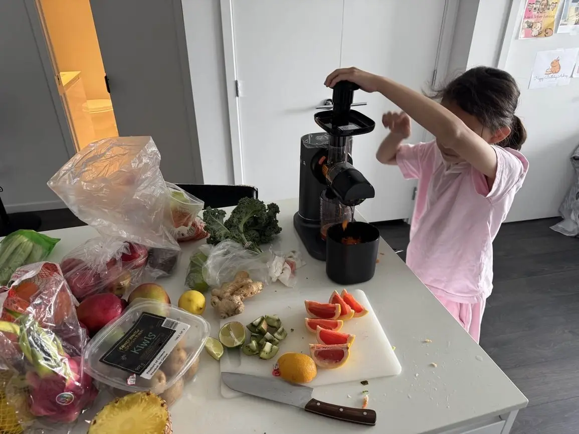 A young client pressing fresh fruit through a juicer during a session